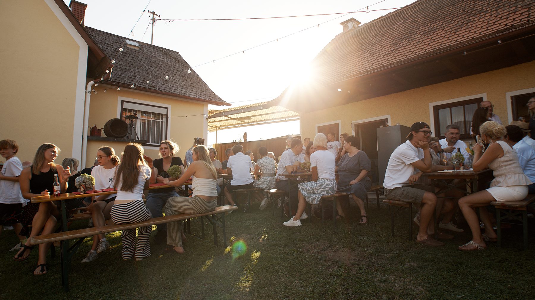 Hochzeitsgesellschaft an langen Tischen im Abendlicht